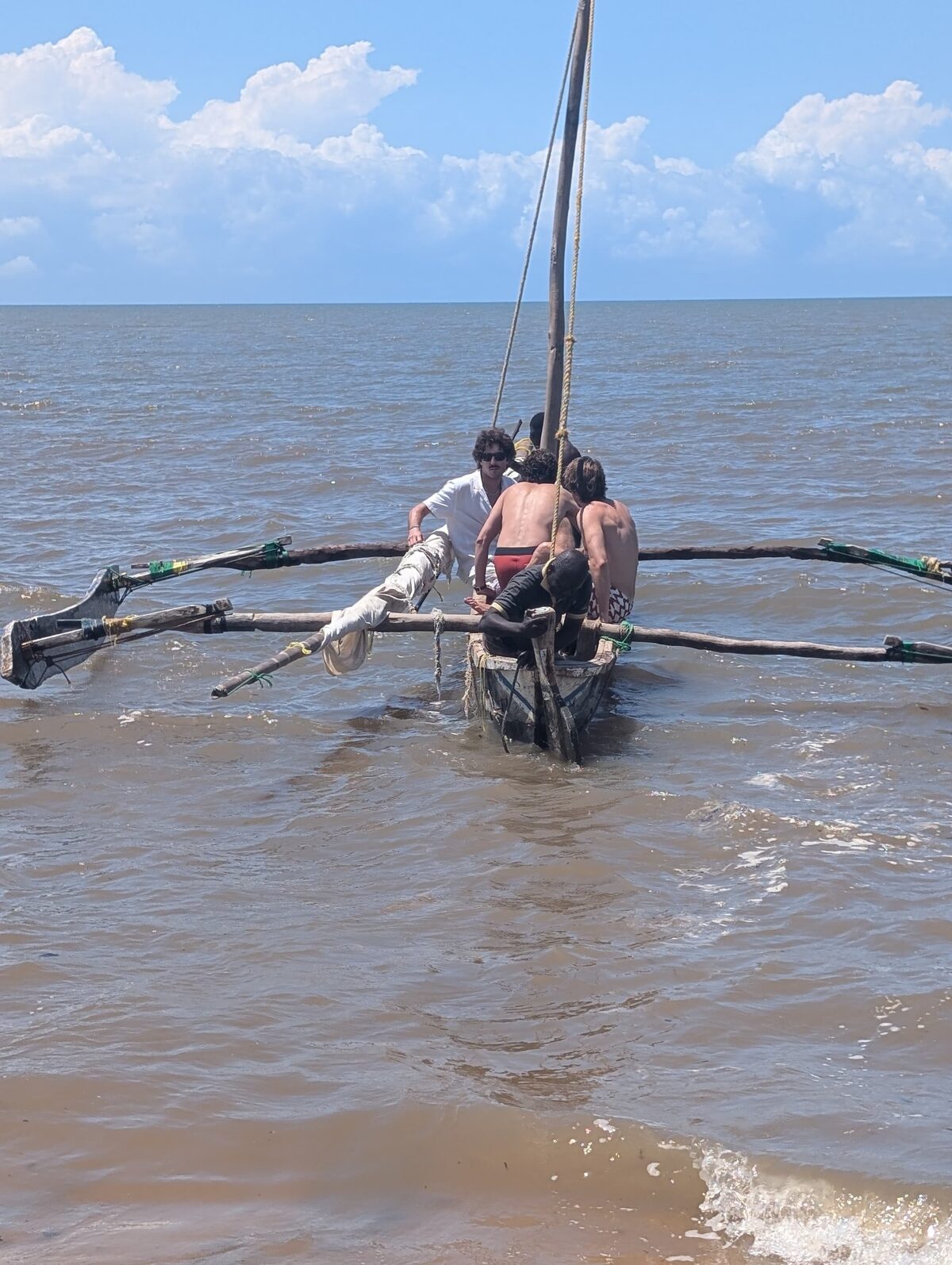 Huéspedes subiendo a la canoa desde la orilla, con la vela izada