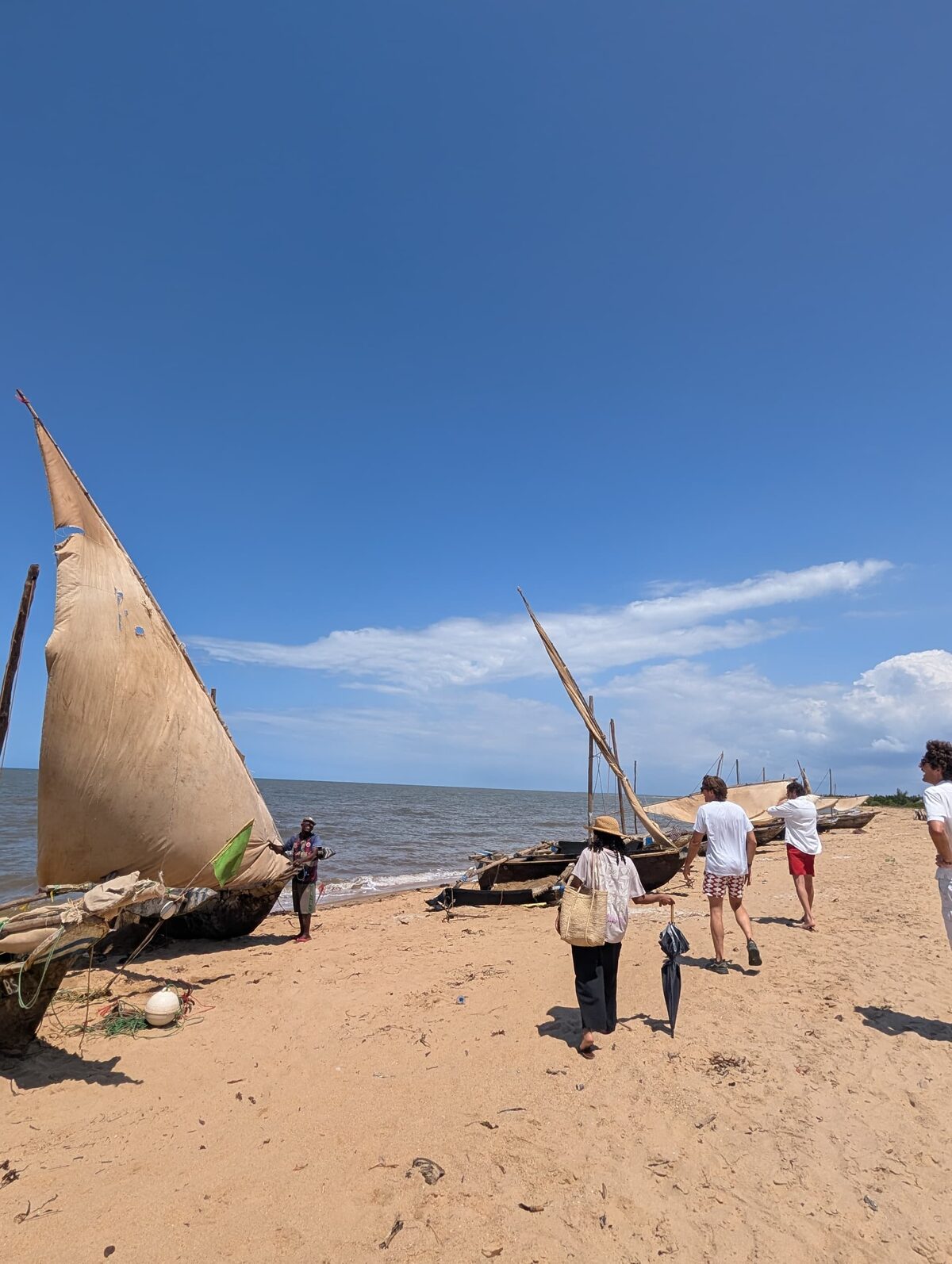 Dhows tradicionales varados en la arena de Saadani, con huéspedes caminando por la orilla