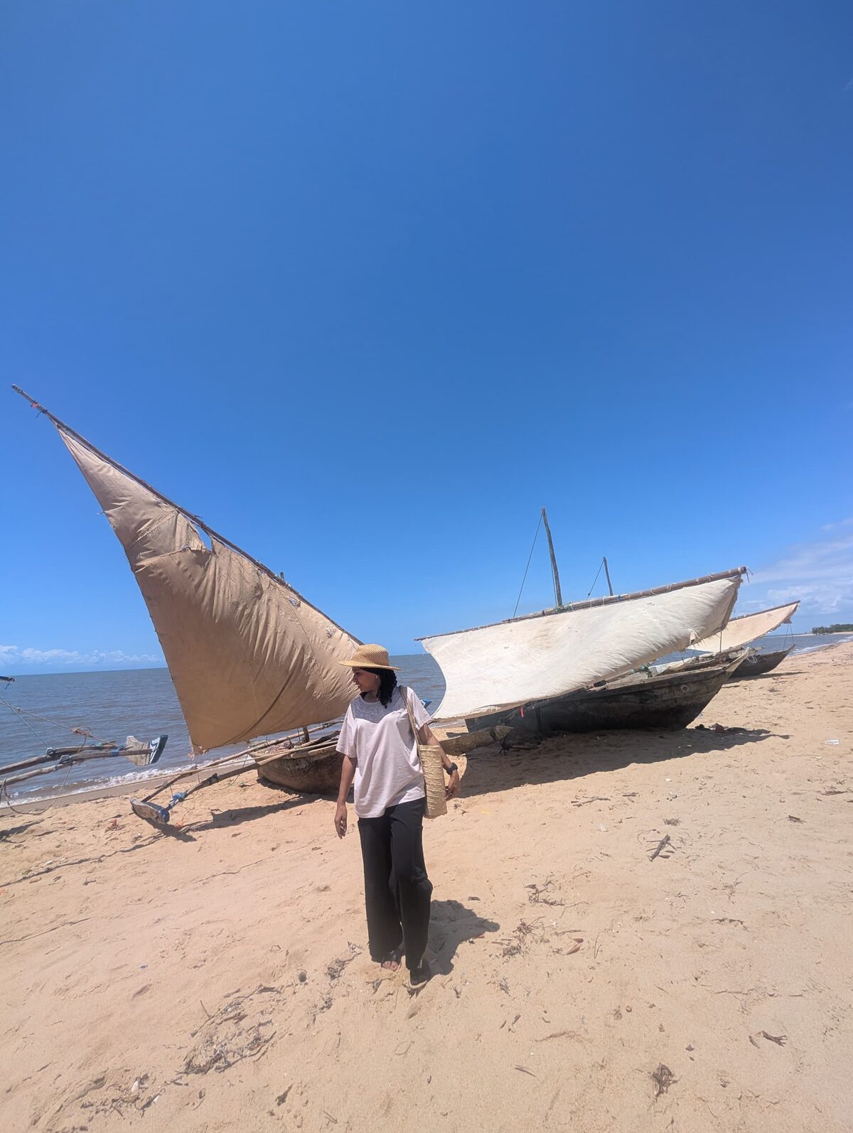 Un dhow con la vela izada sobre la arena, con el océano Índico detrás