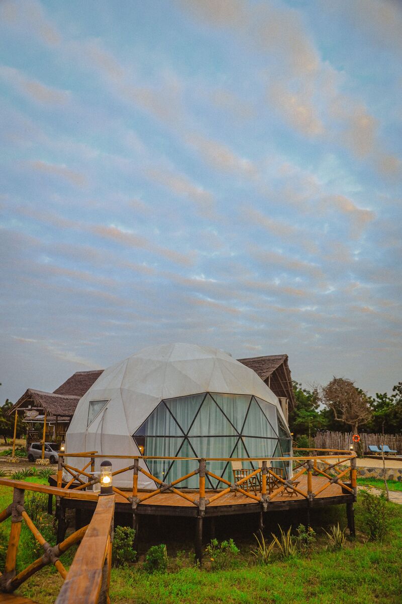 The domes from outside — The tented domes on their platforms, among the palms and facing the ocean.