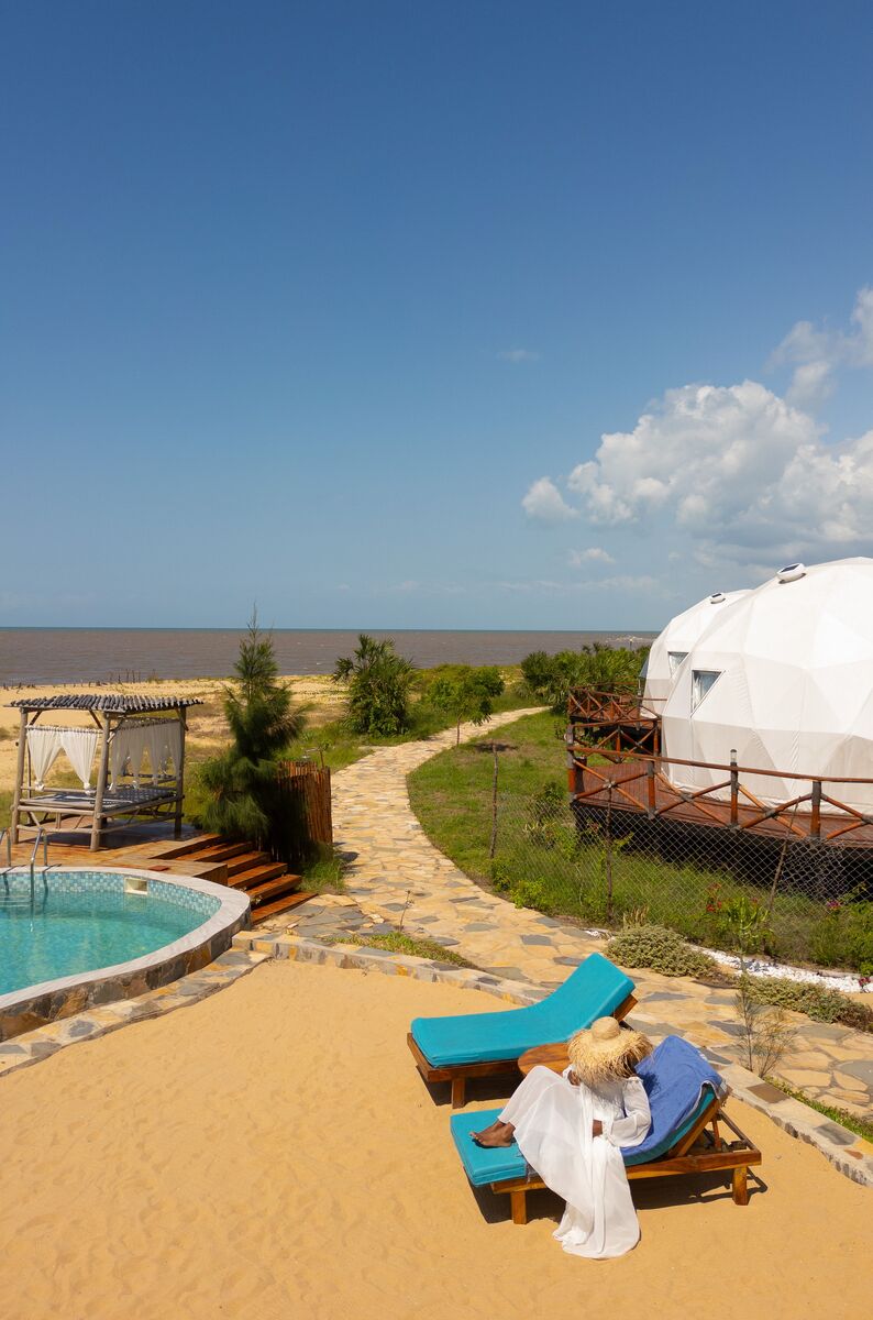 The domes from outside — The tented domes on their platforms, among the palms and facing the ocean.