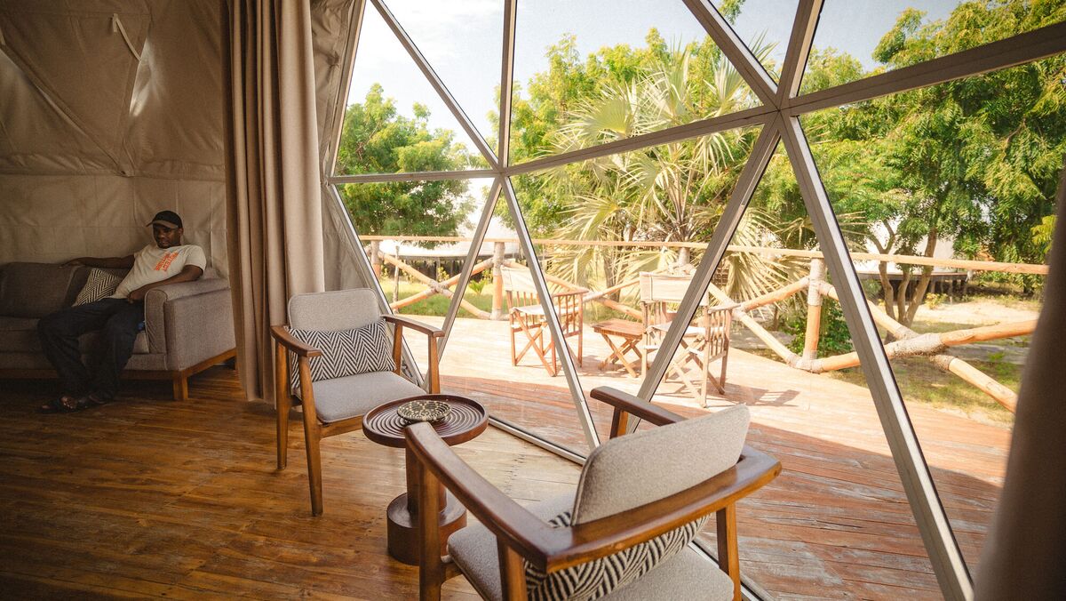 Inside a Family Garden dome at Cterra Saadani, with the loft rail and the bench at the foot of the bed