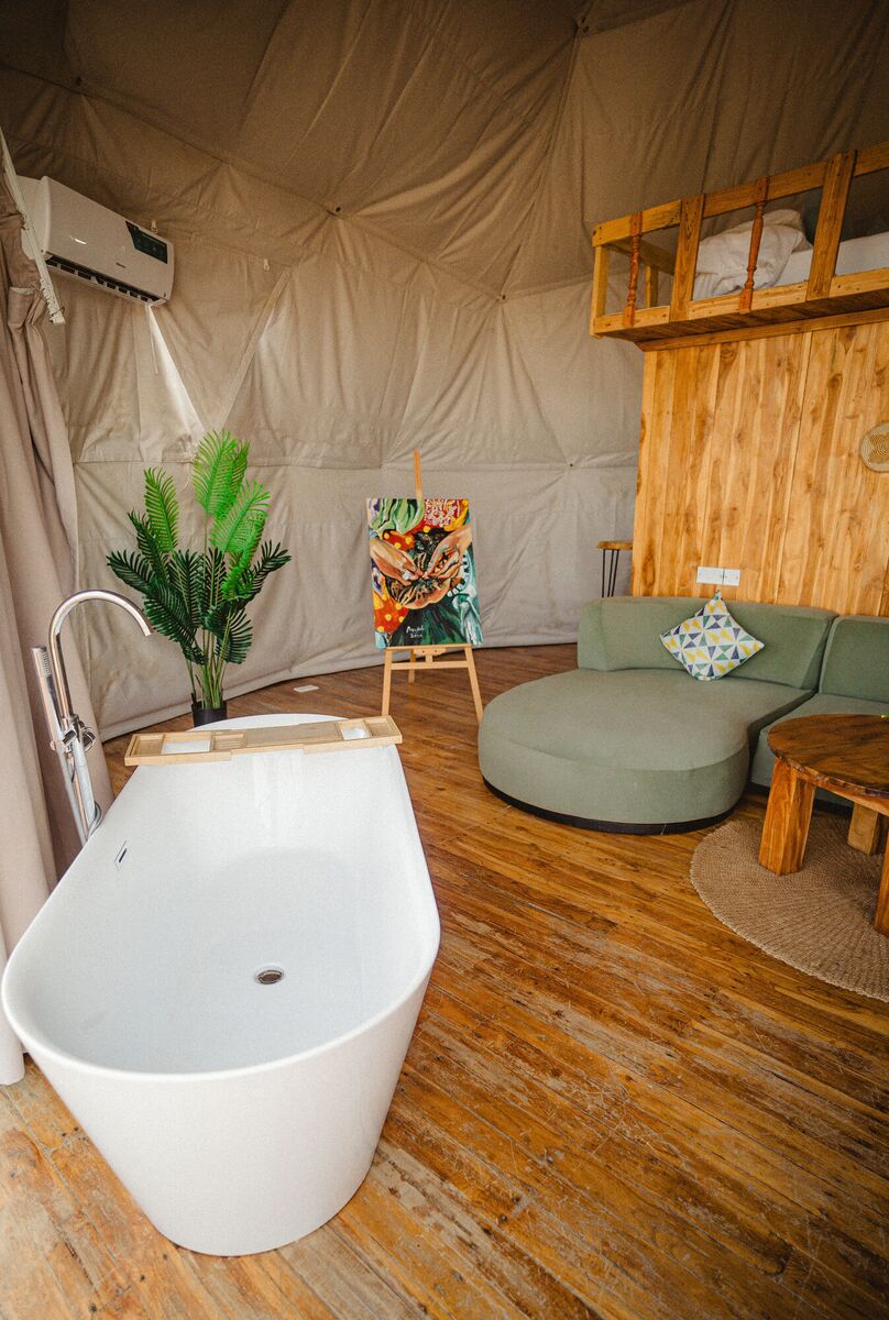 The Honey Suite at Cterra Saadani, with the green sofa and the freestanding bath
