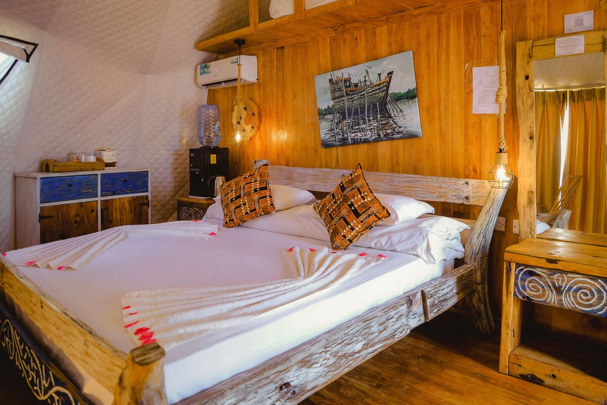 Inside a Standard tent at Cterra Saadani, with the timber wall and the driftwood bed