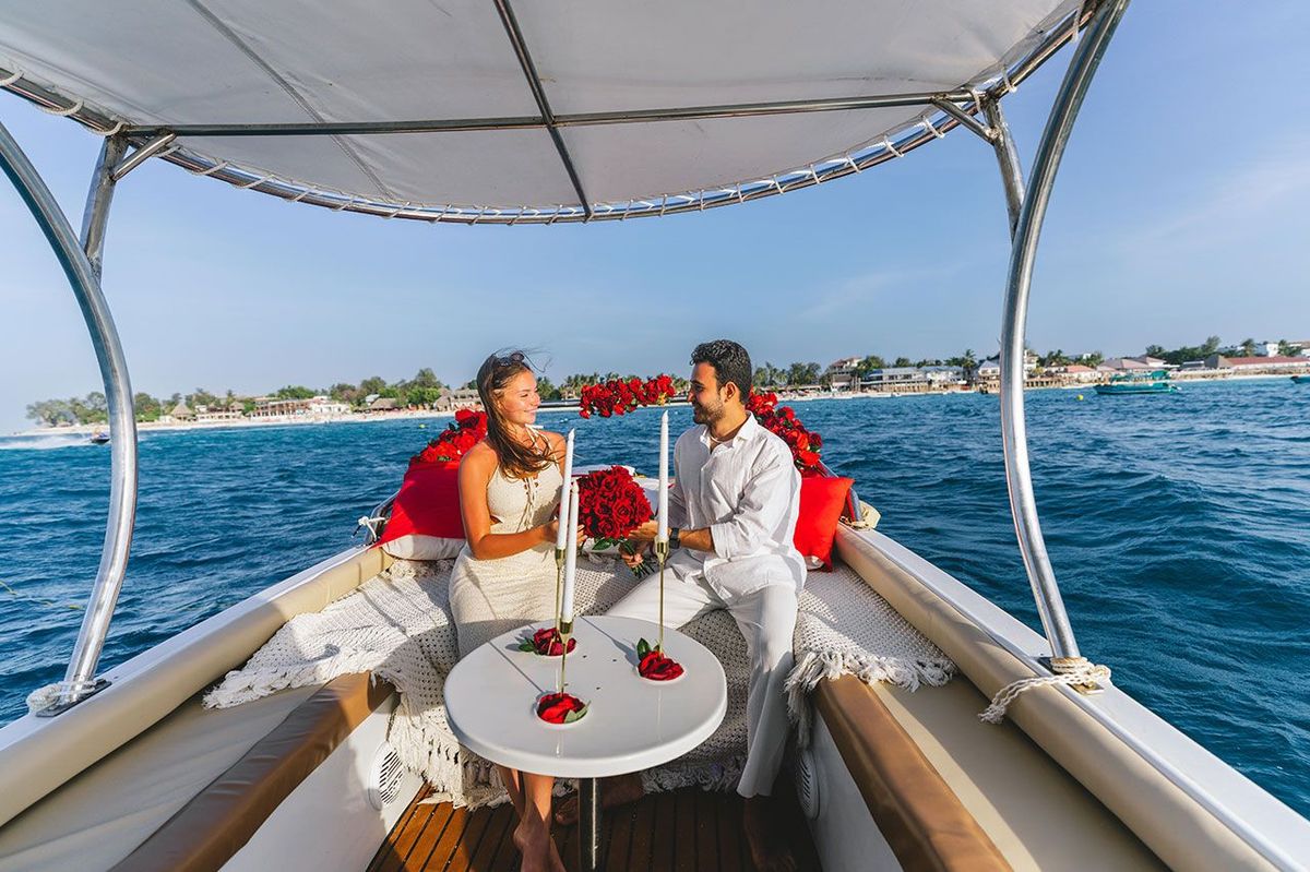 Une table dressée pour deux sur le pont, des roses le long du bastingage et la côte au fond
