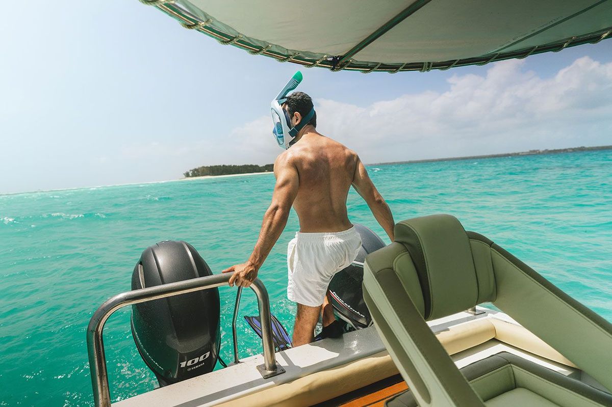 Un hôte masque de snorkeling sur le visage, à la poupe, prêt à se mettre à l’eau
